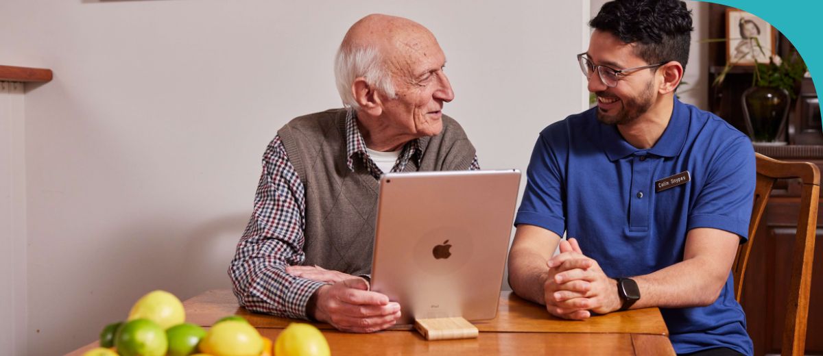 An older man and a woman sit at a table talking face to face