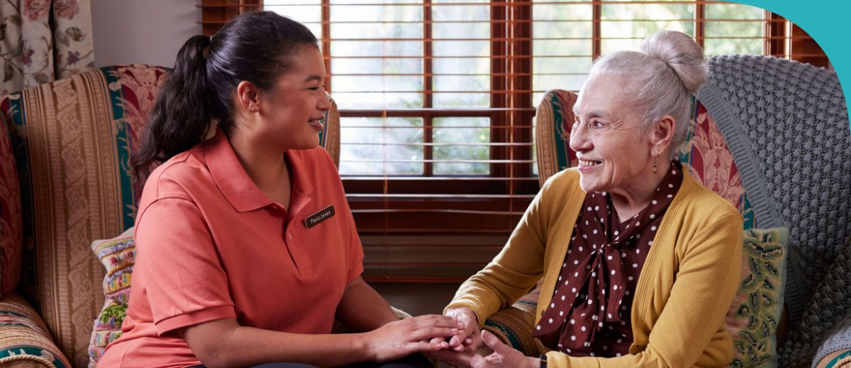 An older man and a woman sit at a table talking face to face