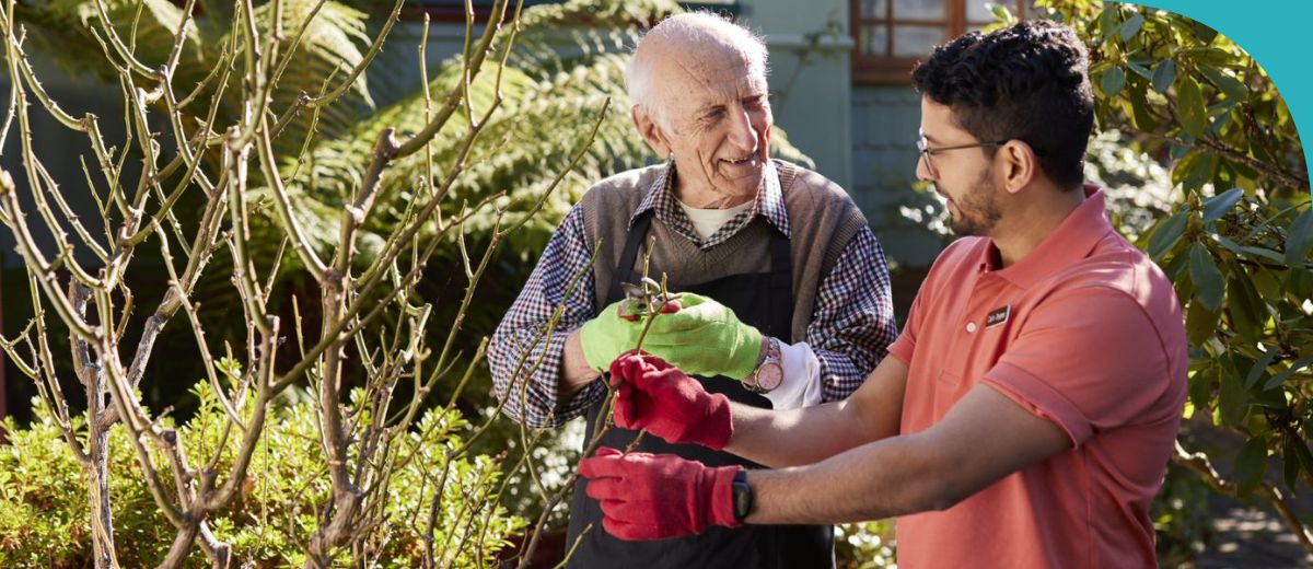 An older man and a younger man gardening and chatting