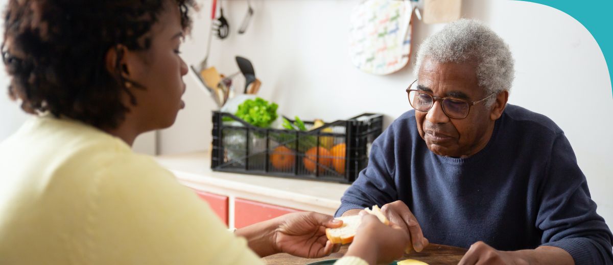 Older man is being served food by an aged care worker.