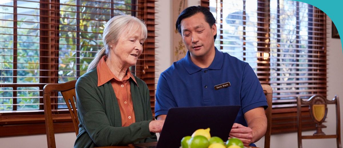 Aged care worker and older lady working on a computer